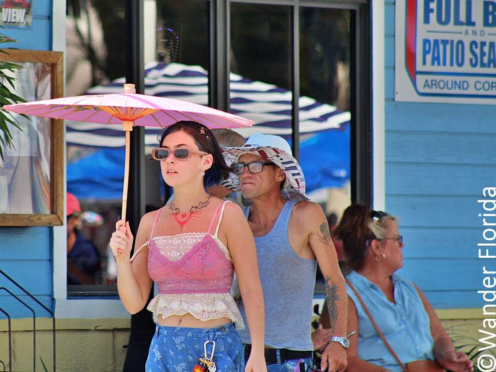 GeckoFest: Gulfport's Epic Way to End the Summer 4 A young woman in a pink top and jeans carries a pink parasol during Geckofest in Gulfport.